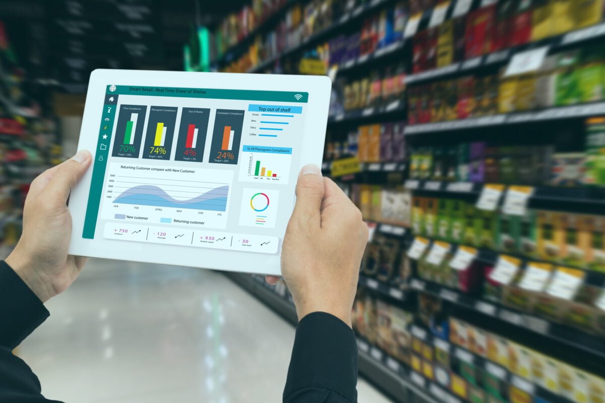 Retailer holds tablet and use augmented reality technology to monitor data.